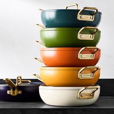 a stack of different colored pots with gold handles