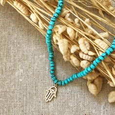 Turquoise is called the self acceptance stone. It promoted self-esteem and unconditional love. Our hand beaded necklace also has a Hamsa charm pendant in goldtone plated brass with cubic zirconia stones. The Hamsa symbol dates back to ancient Mesopotamia where the open right hand is seen in artifacts and in the amulets of the goddess Ishtar. Other symbols of divine protection based around the hand include the Hand-of-Venus which was used to protect women from the evil eye and/or boost fertility, Hand-strung Turquoise Pendant Jewelry, Hand-strung Turquoise Pendant, Turquoise Hand-strung Pendant, Spiritual Beaded Turquoise Jewelry, Adjustable Turquoise Pendant Charm Necklace, Turquoise Pendant Beaded Necklace With Natural Stones, Turquoise Beaded Necklaces For Healing, Spiritual Turquoise Beaded Jewelry, Blue Howlite Beaded Necklaces As Gift