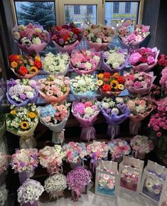 a bunch of flowers that are sitting on a table in front of a store window