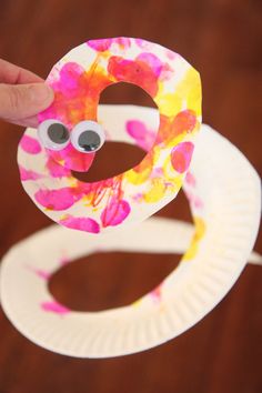 a hand holding up a paper plate with a craft made to look like a donut