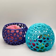 two colorful balls sitting next to each other on top of a white surface with holes in them