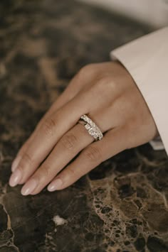 a woman's hand with a diamond ring on her left wrist, sitting on a marble surface