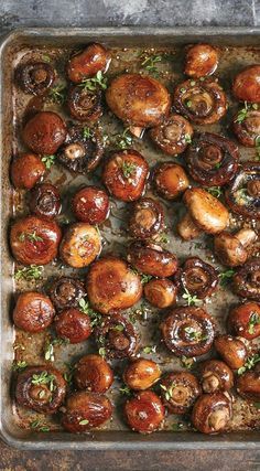 a baking pan filled with cooked mushrooms and garnished with herbs