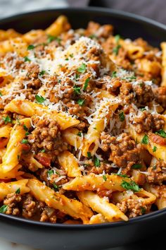 pasta with ground beef and parmesan cheese in a black bowl on a table