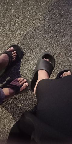 two people wearing black sandals are sitting on the ground