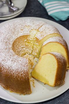 a white plate topped with a cake covered in powdered sugar on top of a table