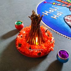 an orange vase with flowers and candles on the floor