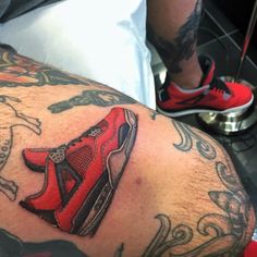 a close up of a person's leg with tattoos on it and a red shoe