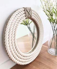 a rope mirror hanging on the wall next to flowers