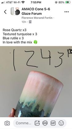 someone is holding up a cup that has been painted with green and pink paint on it