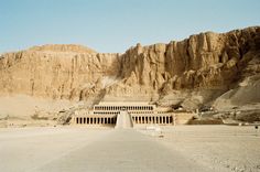 an empty parking lot in front of some large mountains and desert like area with steps leading up to the entrance