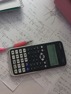 a calculator sitting on top of a table next to a pen and paper