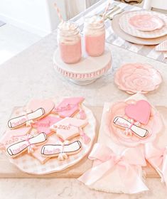 some cookies are on a table with pink decorations