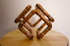 two pieces of copper colored metal sitting on top of a wooden table next to a white wall