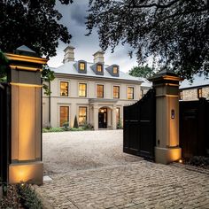 a large white house with two black gates and lights on it's front entrance