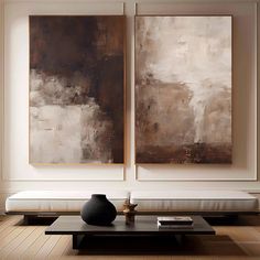 two large paintings hang on the wall above a coffee table in a living room with hardwood floors