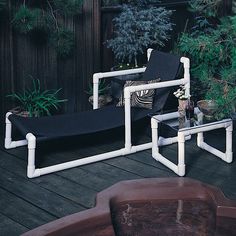 an outdoor lounge chair made out of pipes and pipe tubes is sitting on a deck