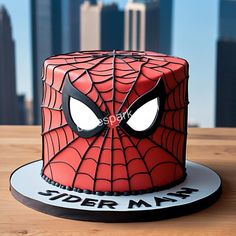 a spiderman cake on a wooden table in front of a cityscape with skyscrapers