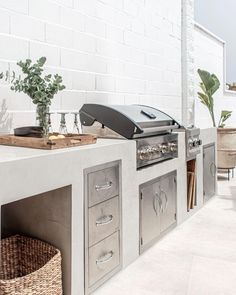 an outdoor bbq with grill, sink and potted plant on the counter top