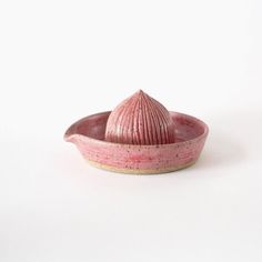 a pink ceramic bowl with a small cone on the top, sitting in front of a white background