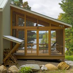 a small house with a porch and deck on the side of it, surrounded by rocks