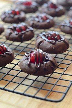 some cookies are cooling on a rack and one is covered in chocolate frosting with red sprinkles