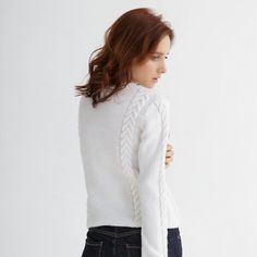 a woman in jeans and a white sweater is looking down at the back of her body