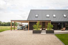 a house with a car parked in front of it next to a gravel driveway and green grass