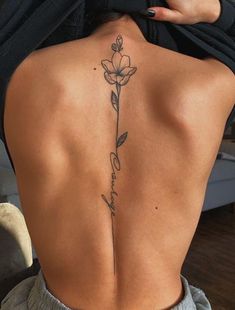 the back of a woman's neck with a flower tattoo on her lower back