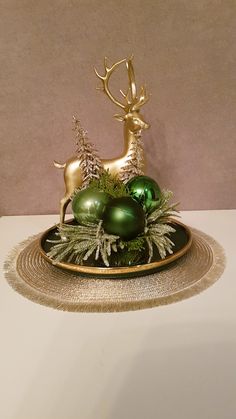 a plate topped with green ornaments and gold deer figurines on top of it