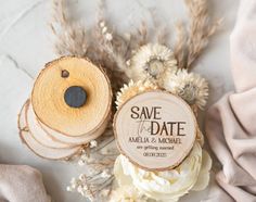 save the date magnets are sitting on top of some flowers and wood slices in front of them