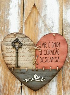 a heart shaped sign hanging on the side of a wooden fence with an old key attached to it