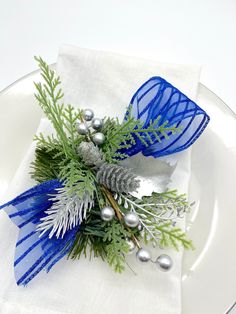 a white plate topped with a blue and silver boutonniere on top of a napkin