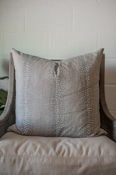 a pillow sitting on top of a chair next to a plant