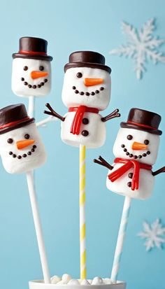 four marshmallow snowmen on sticks in a cup