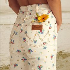 Good Days Start With Good Denim, And You Can't Go Wrong With The She's Cheeky Pant. Serving Up A Hip-Hugging Fit That Can't Be Beat, These White Denim Beauties Take A Timeless 5-Pocket Design And Go Full Flower Power With A Sweet Floral Print. They're High-Waisted, Button Up The Front, And Feature The Iconic Wrangler Stitching On The Back Pockets. To Top It All Off, These Cheeky Wonders Are Made With Eco-Conscious Cotton Denim. Our Eco-Conscious Cotton Is Farmed And Produced In A Way That Aims To Reduce Its Environmental Impact And Improve Working Conditions. The Billabong X Wrangler Collection Invites You On A Ride Where Two Celebrated Brands Weave Their Stories Together And Take A Journey White Retro Jeans For Spring, White Floral Print Jeans For Spring, Retro White Jeans For Spring, White Cotton Jeans With Floral Print, Casual White Jeans With Floral Print, White High-rise Retro Jeans, White Floral Print Cotton Jeans, White Retro High Rise Jeans, Retro High Rise White Jeans