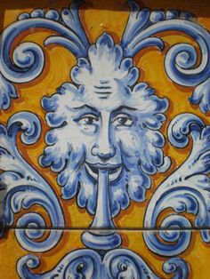 a painted tile with an image of a man's face in blue and yellow