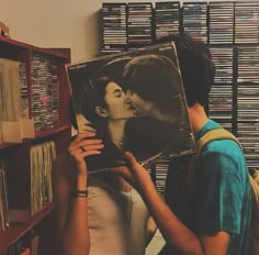 a man and woman kissing each other in front of a record shelf with records on it