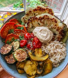 a blue bowl filled with lots of different types of food on top of a table