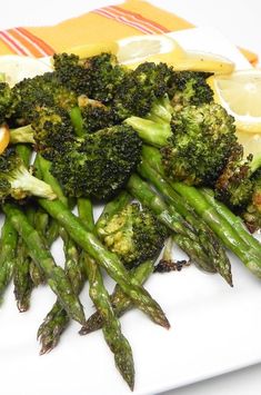 asparagus and lemon wedges on a plate with broccoli florets