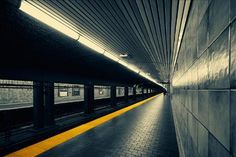 an empty subway station with yellow line on the floor