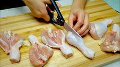 a person cutting up raw chicken on a wooden cutting board with a pair of scissors