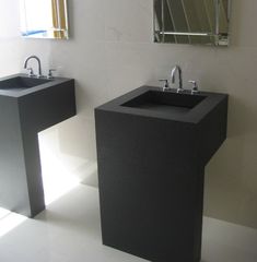 two black sinks sitting next to each other in a bathroom under a mirror on the wall