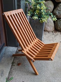 a wooden lawn chair sitting next to a potted plant on the side of a building