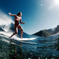 a woman riding a surfboard on top of a wave