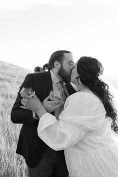 a bride and groom kissing in a field