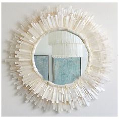 a mirror that is hanging on the wall next to a mirror with some sticks sticking out of it