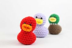 three small crocheted ducks sitting next to each other on a white surface,