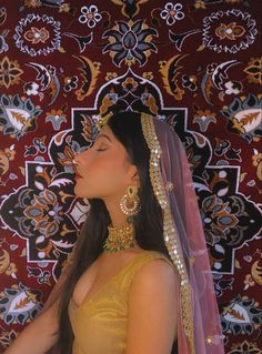 a woman in a yellow dress with a veil on her head looking up to the sky