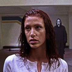 a woman standing in front of a man with a ghost mask on her head and wearing a white shirt